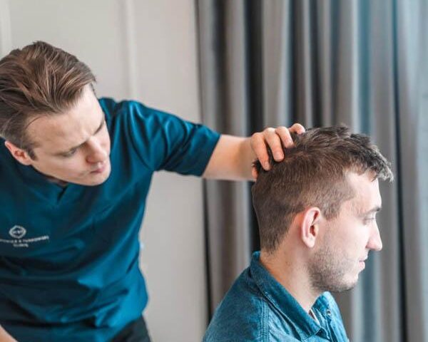 Konsultacja trychologiczna i badanie skóry głowy w PT CLINIC Lekarz trycholog przeprowadzający konsultację i badanie skóry głowy u pacjentki w klinice