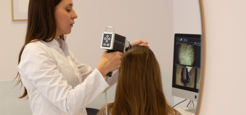 Badanie trichoskopowe w PT CLINIC: Diagnostyka miniaturyzacji mieszków włosowych przed zmianą leczenia. Precyzyjne badanie trichoskopowe skóry głowy pacjenta z łysieniem androgenowym przy użyciu cyfrowego trichoskopu medycznego w PT CLINIC Warszawa.