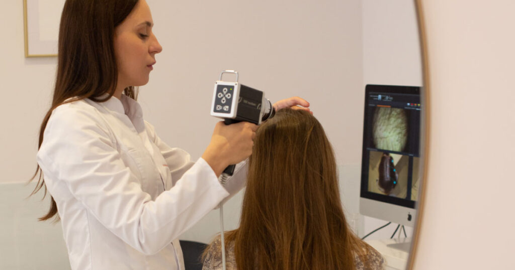 Precyzyjne badanie trichoskopowe skóry głowy pacjenta z łysieniem androgenowym przy użyciu cyfrowego trichoskopu medycznego w PT CLINIC Warszawa.